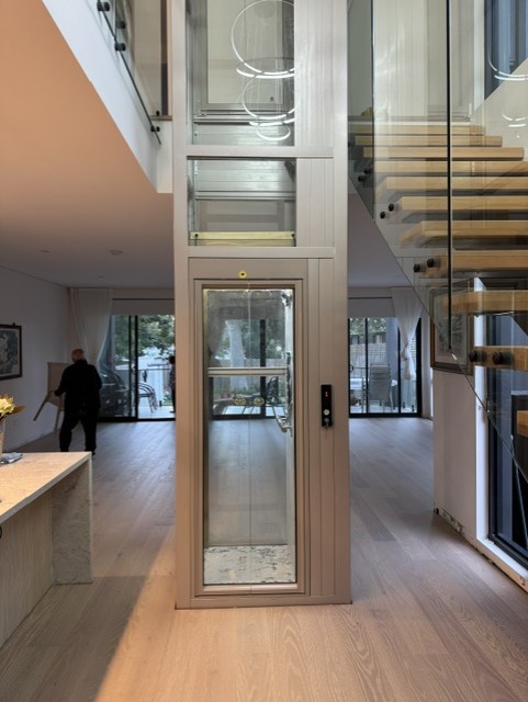 Glass shaft home elevator alongside staircase